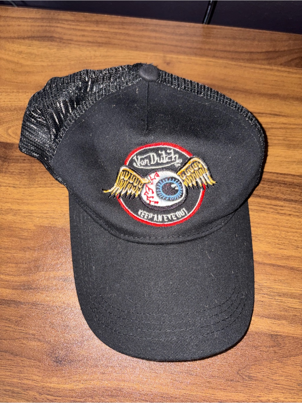 Black Von Dutch trucker hat with a winged flying eyeball patch on the front panel